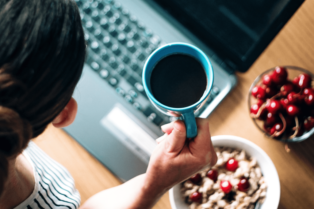 コーヒー、朝食をとりながらパソコンを見る女性