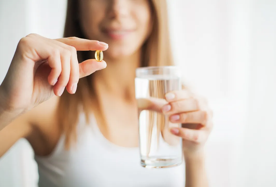 錠剤と水を持つ女性